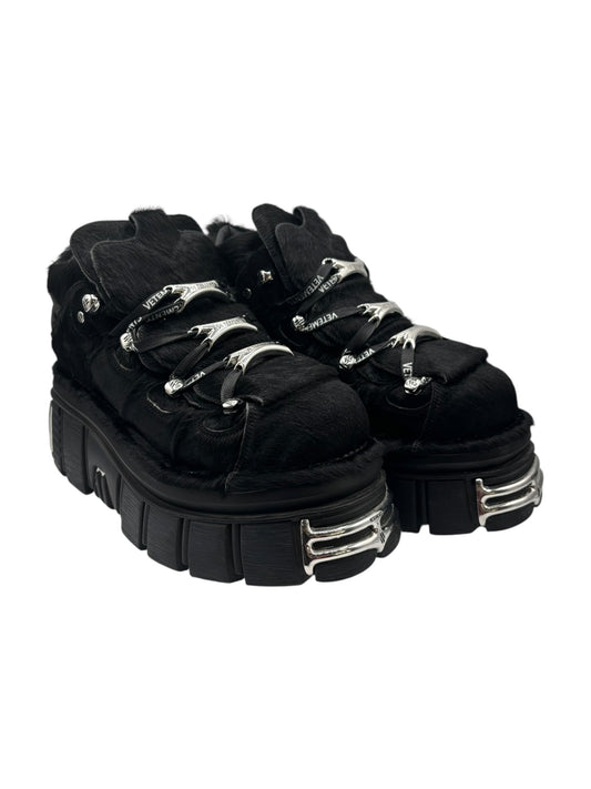 Black fur platform boots, side angle with chunky sole and silver buckle straps