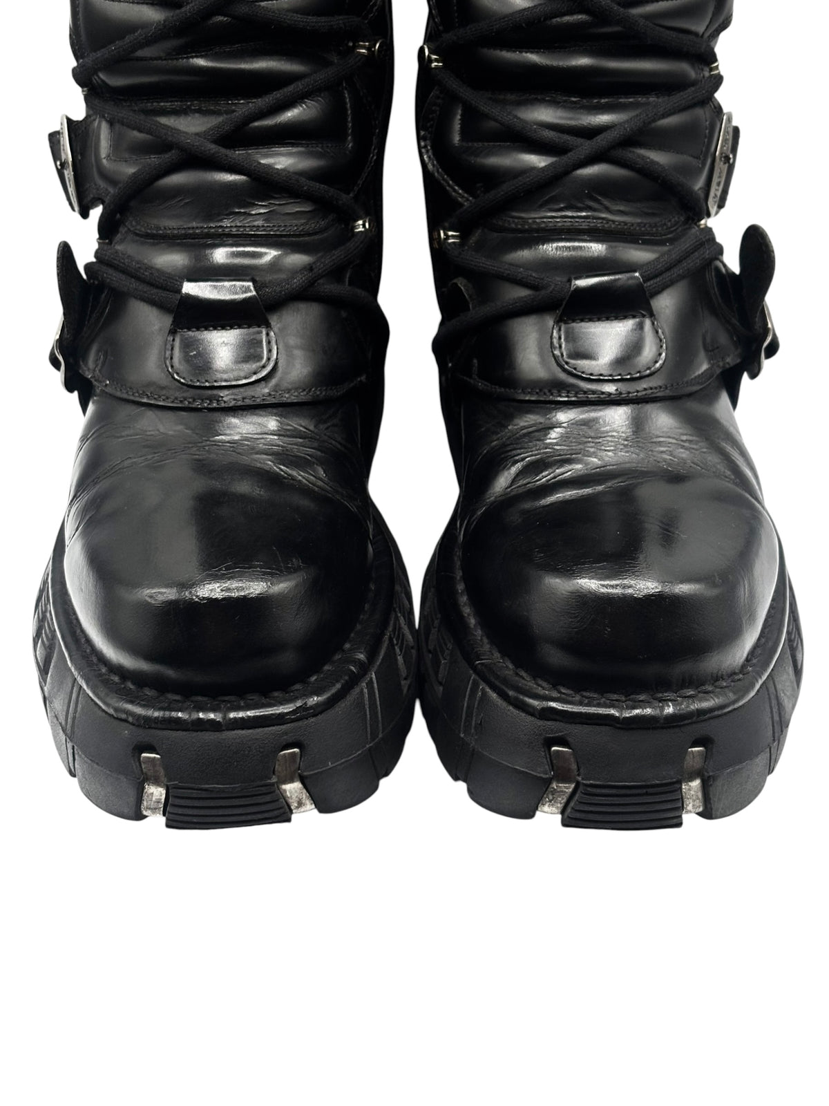 Black leather boots close-up of laces, front straps, and chunky tread outsole.