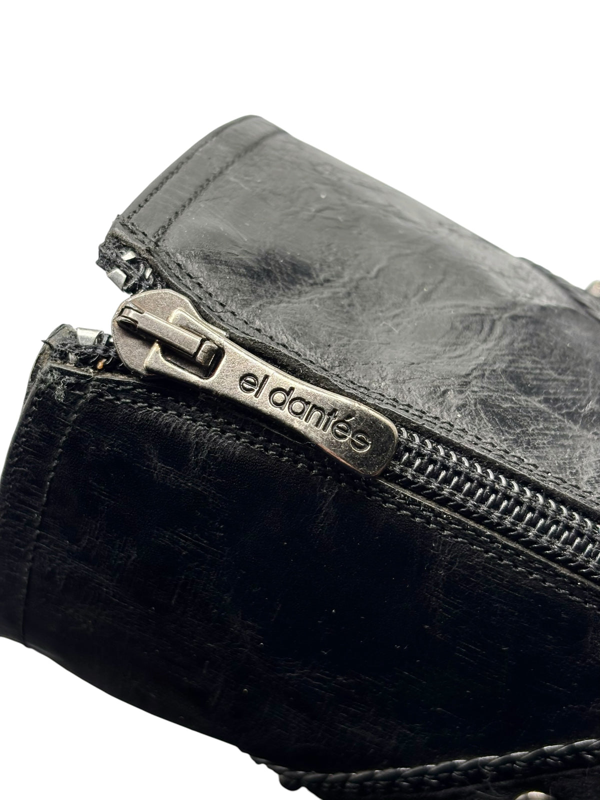 Knee-high boot zipper close-up with metal pull and el dantes logo on leather