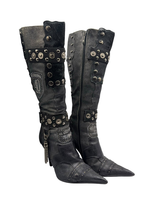 Side view of two dark leather knee-high boots with studded cuffs, pointed toe, and heel.