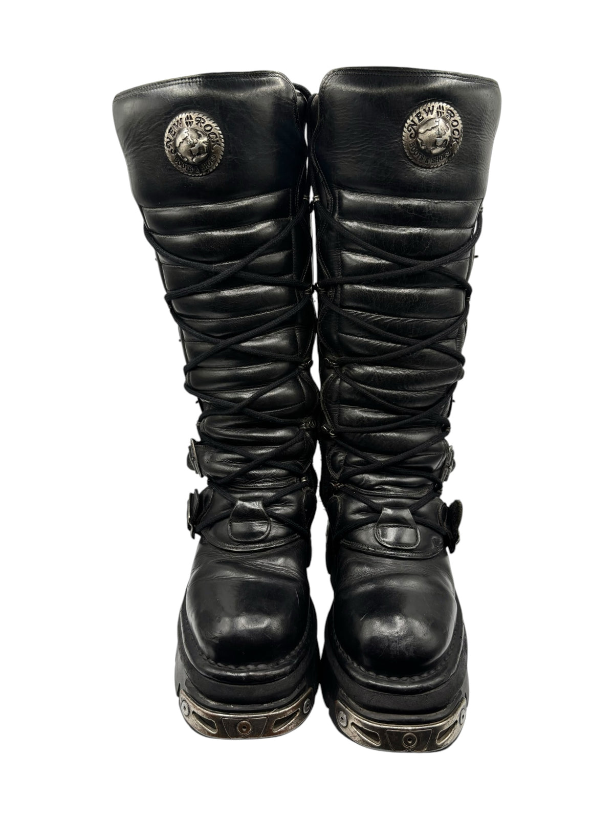 Front view of black knee-high boots with crisscross laces and circular “NEW ROCK” emblem
