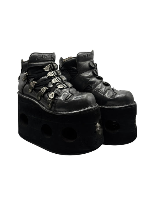 Black leather platform lace-up boots side view with metal hardware and thick sole cutouts.