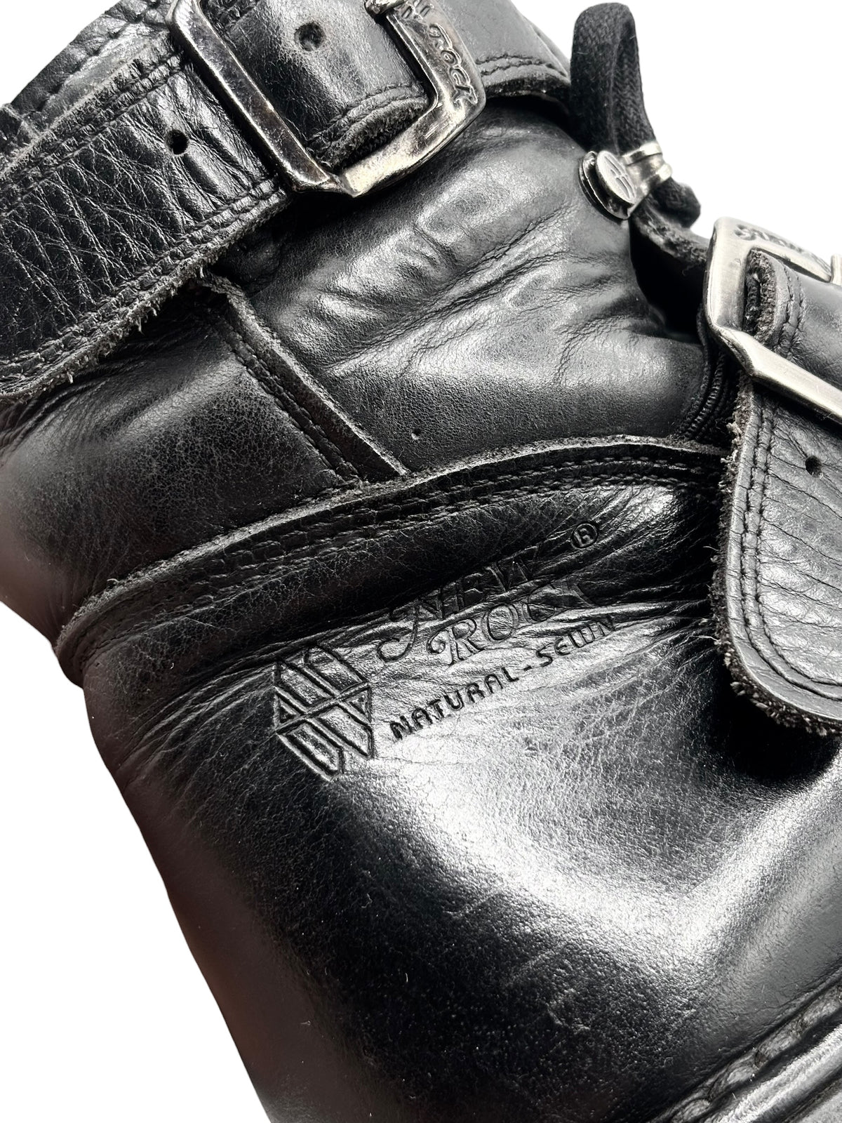 Close-up of black leather raised heel ankle boot with embossed logo and strap