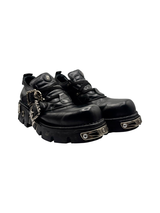 Black ankle boots angled side view with metal hardware and chunky tread sole.
