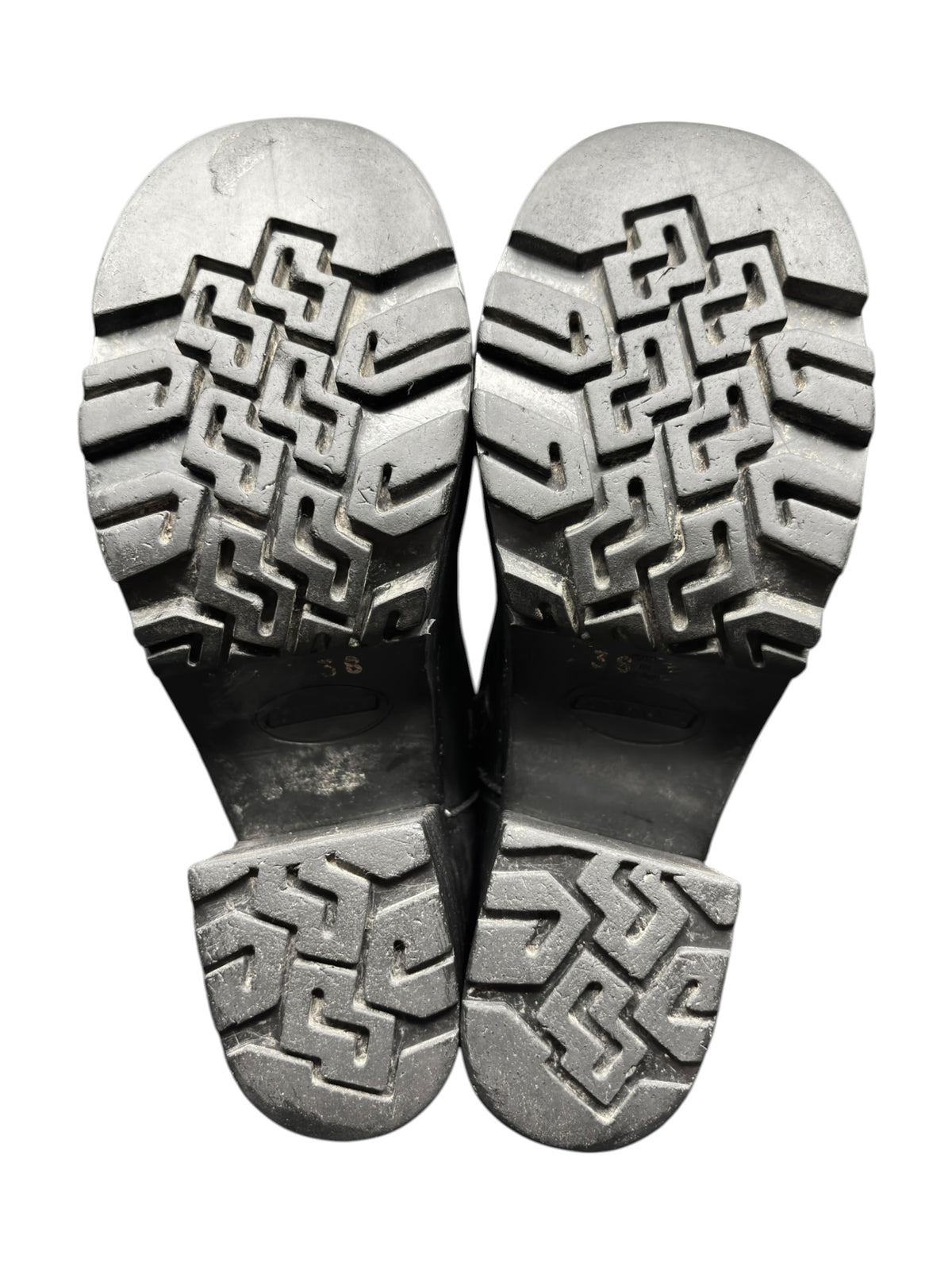 Pair of dark boots with geometric rubber outsole tread, showing undersides