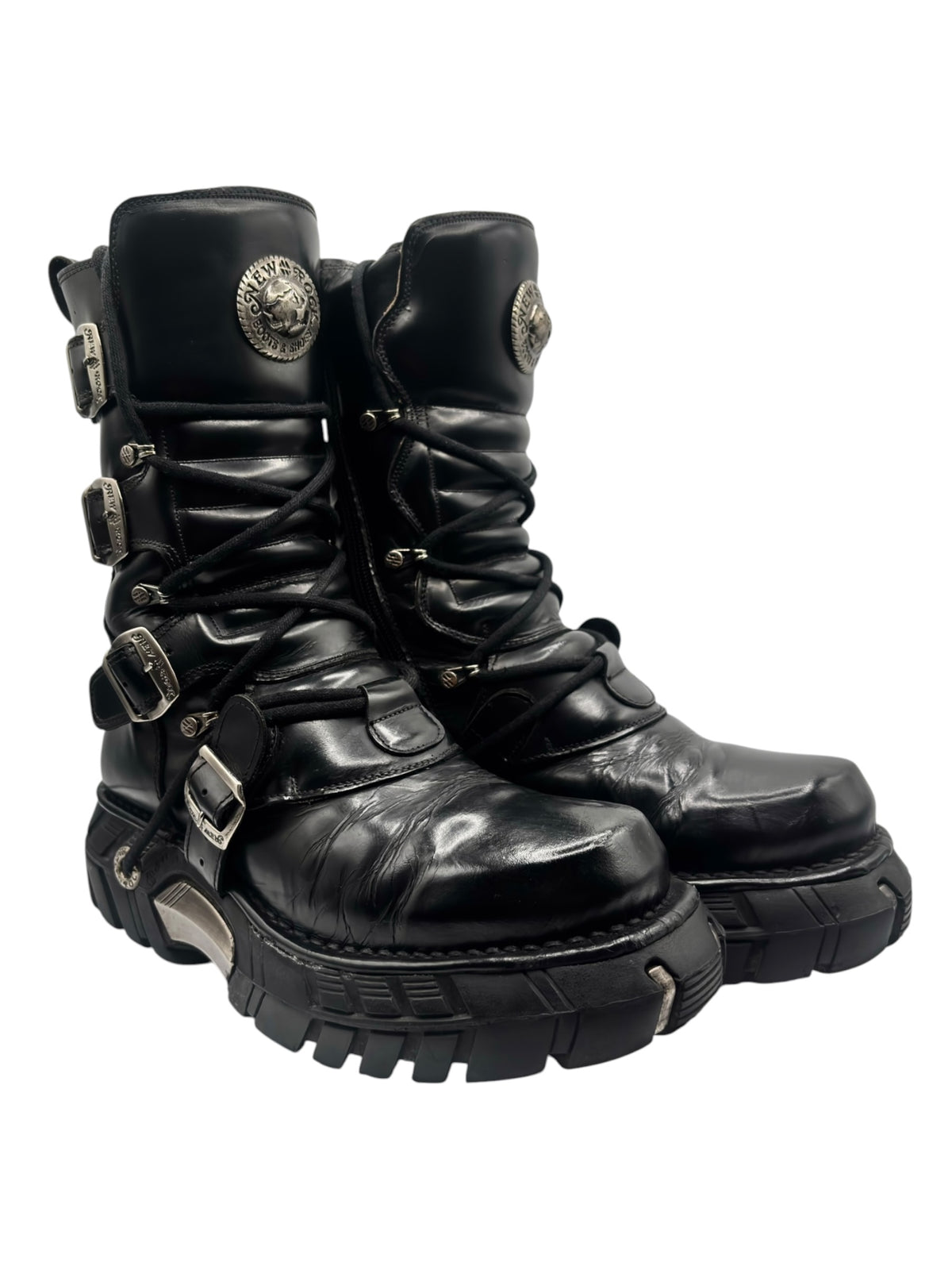 Black lace-up platform boots with buckled straps and round emblem at ankle