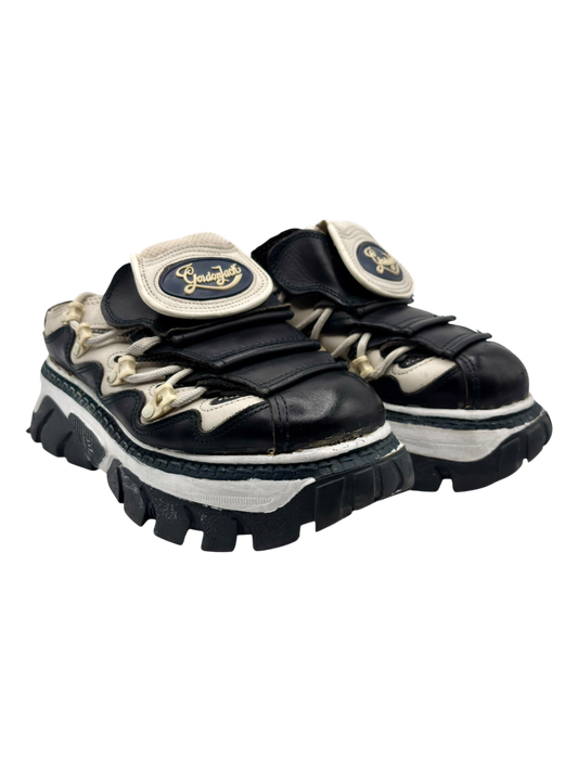 Dark platform lace-up boots with cream trim, chunky rubber sole, logo patch on tongue