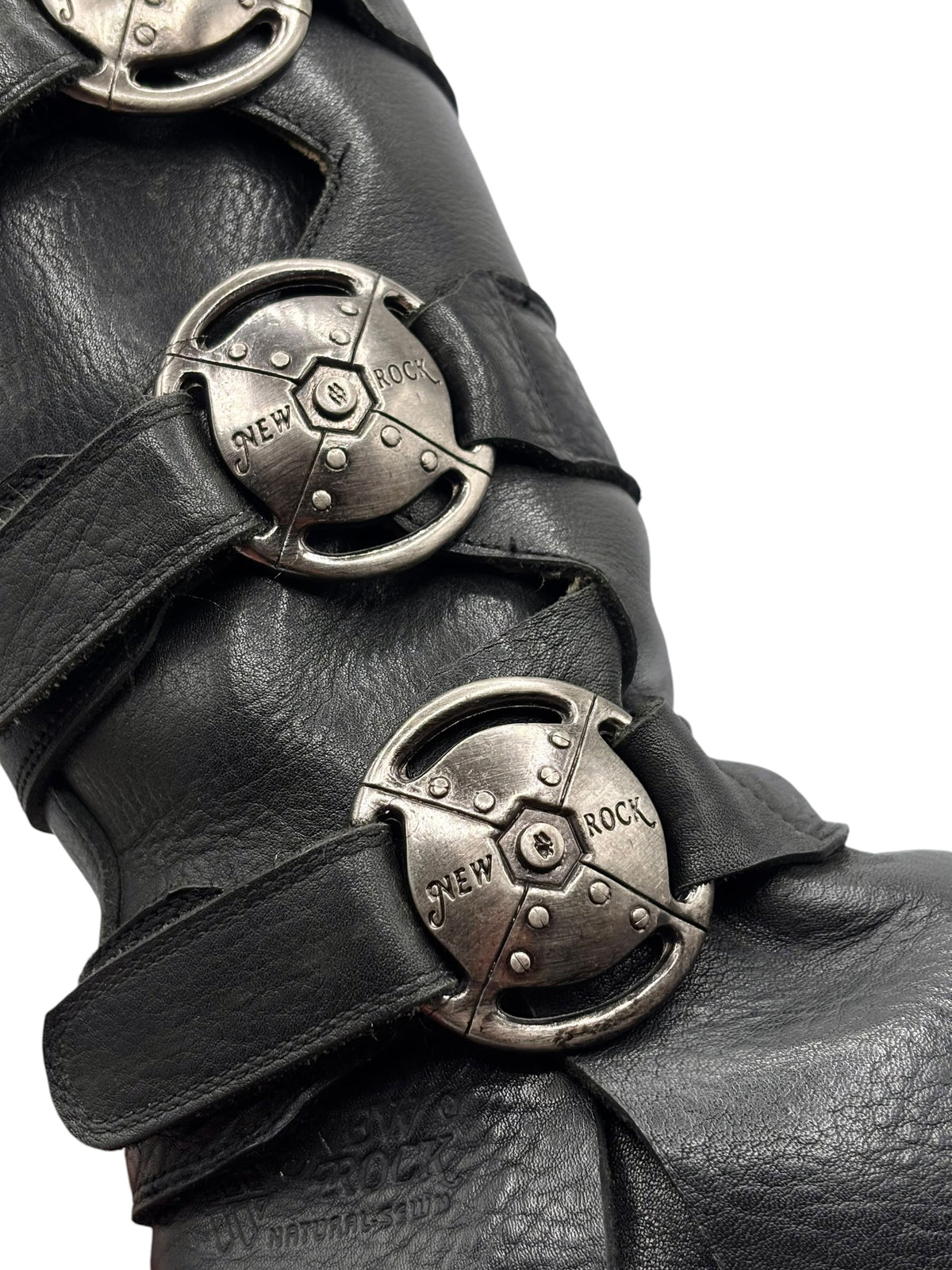 Close-up of knee-high boots with multiple circular silver buckles on straps