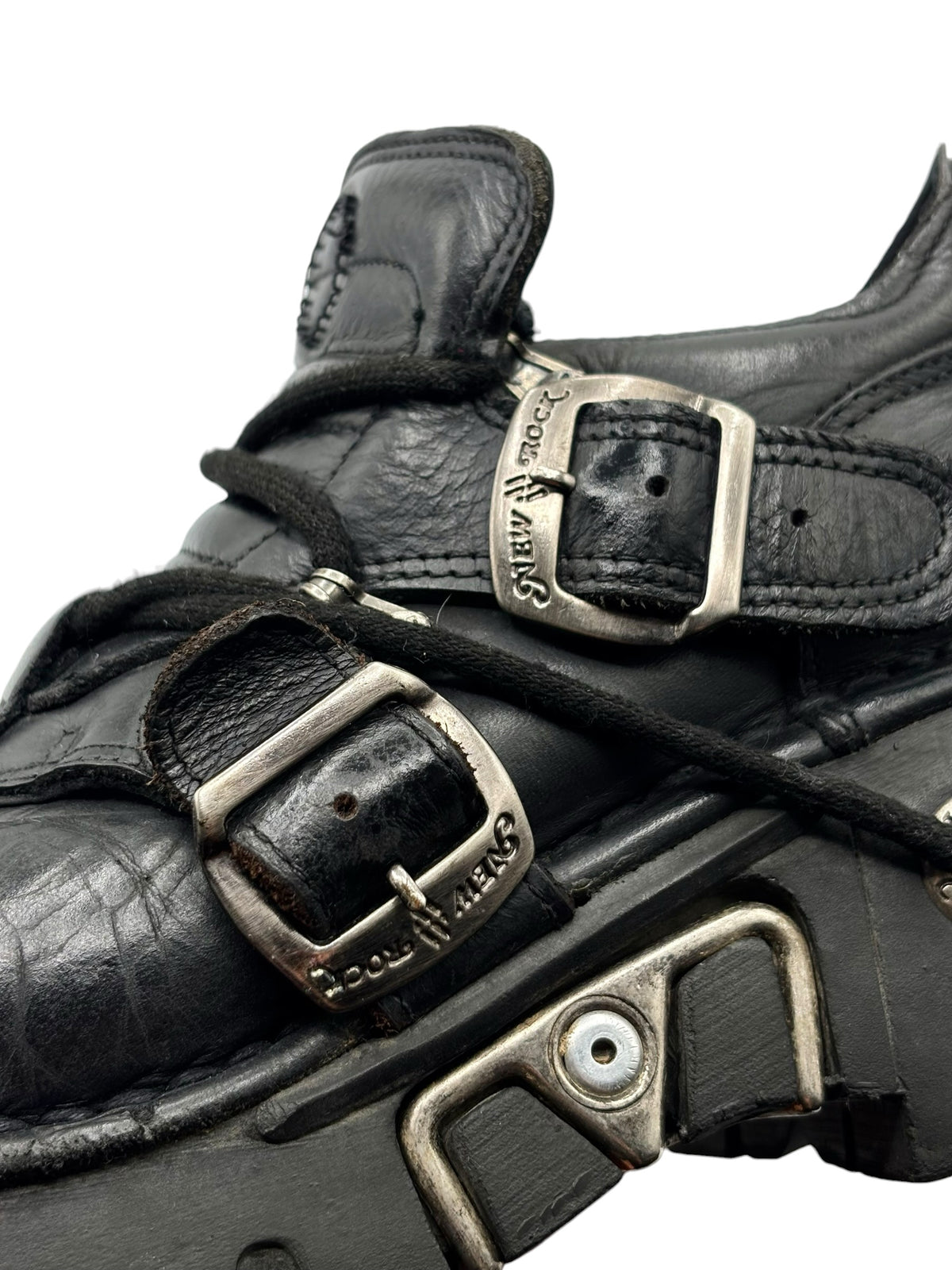 Close-up of black ankle boot straps with metal buckles and “New Rock” branding.