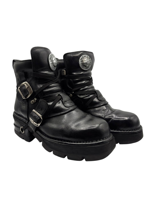 Black leather lace-up boots with raised heel, front buckles, and metal emblem buttons.