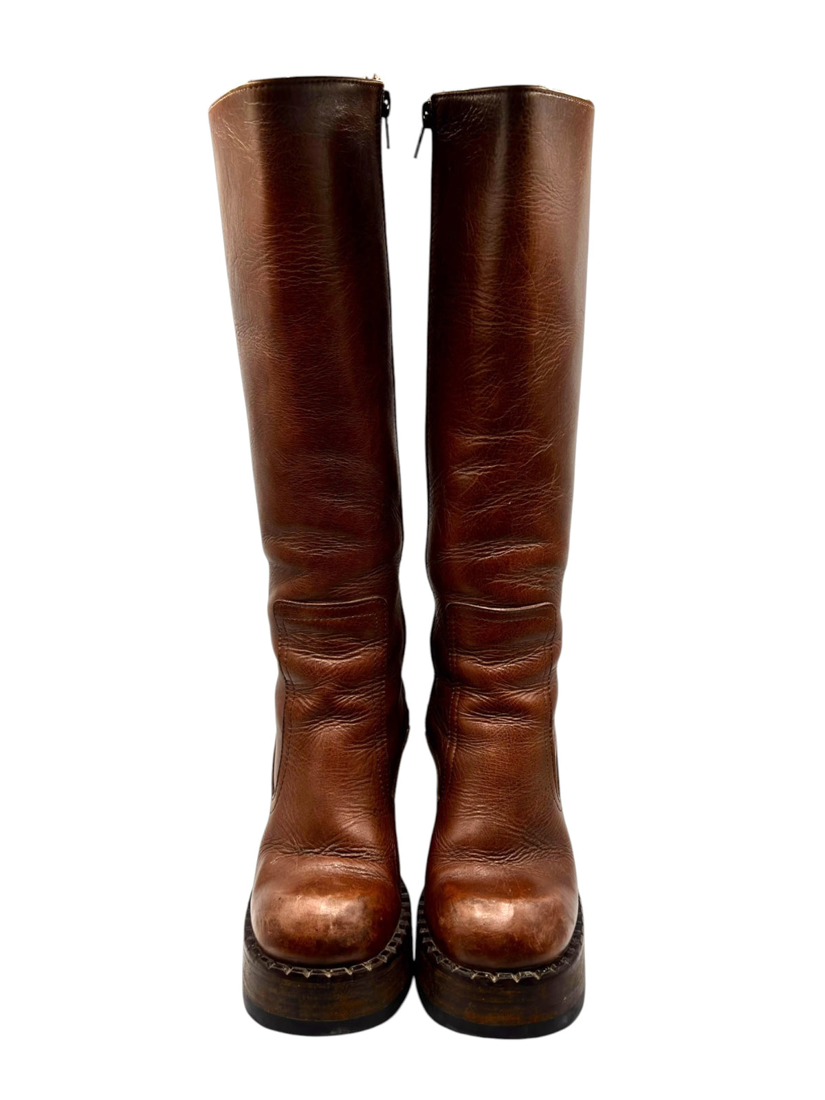 Brown knee-high block platform boots with side zippers and distressed leather