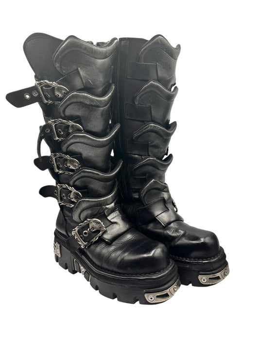 Knee-high black boots with silver buckle details, layered shaft panels, thick tread sole.