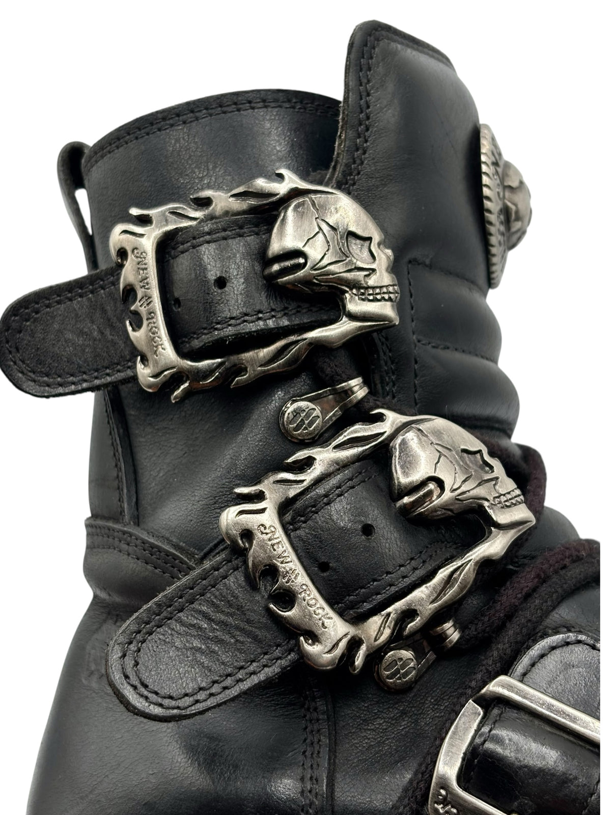 Close-up of black boot with silver-tone skull buckle ornaments and stitching