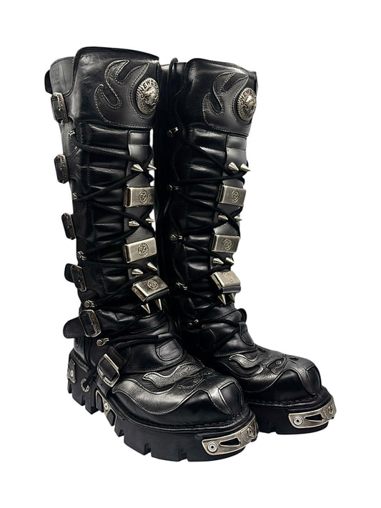Black knee-high leather boots with silver toe trim, studded spiked sole and strap buckles