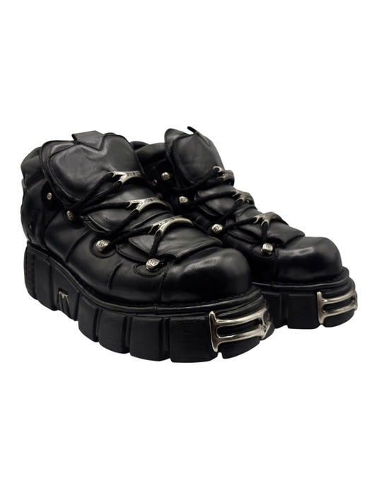 Black lace-up platform boots, side view, with metal eyelets and stacked heel sole
