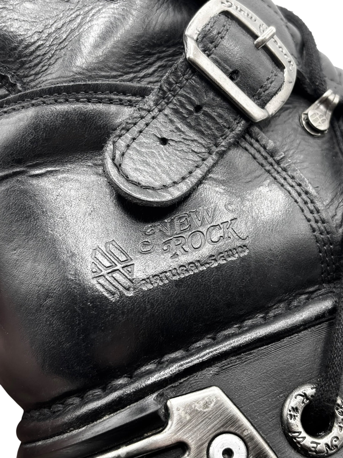 Close-up of black leather ankle boot upper with strap buckle and “NEW ROCK” logo