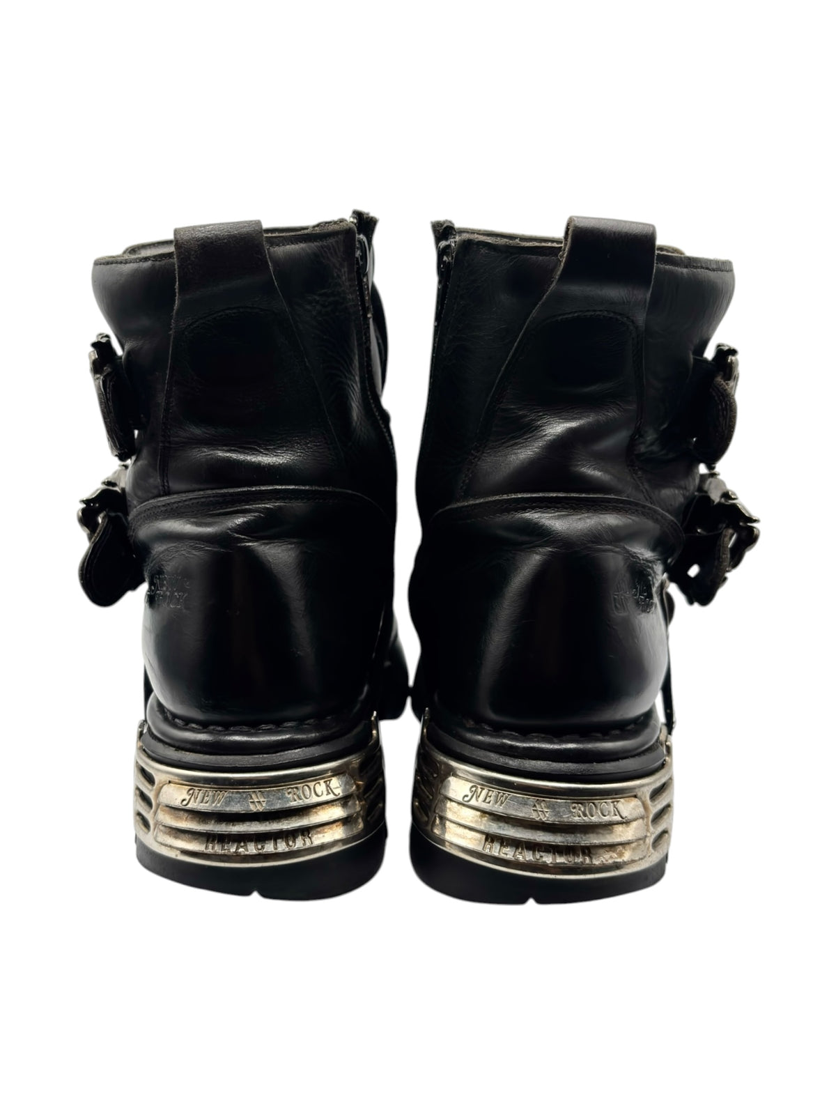 Pair of black boots viewed from back with straps and thick silver-trimmed soles