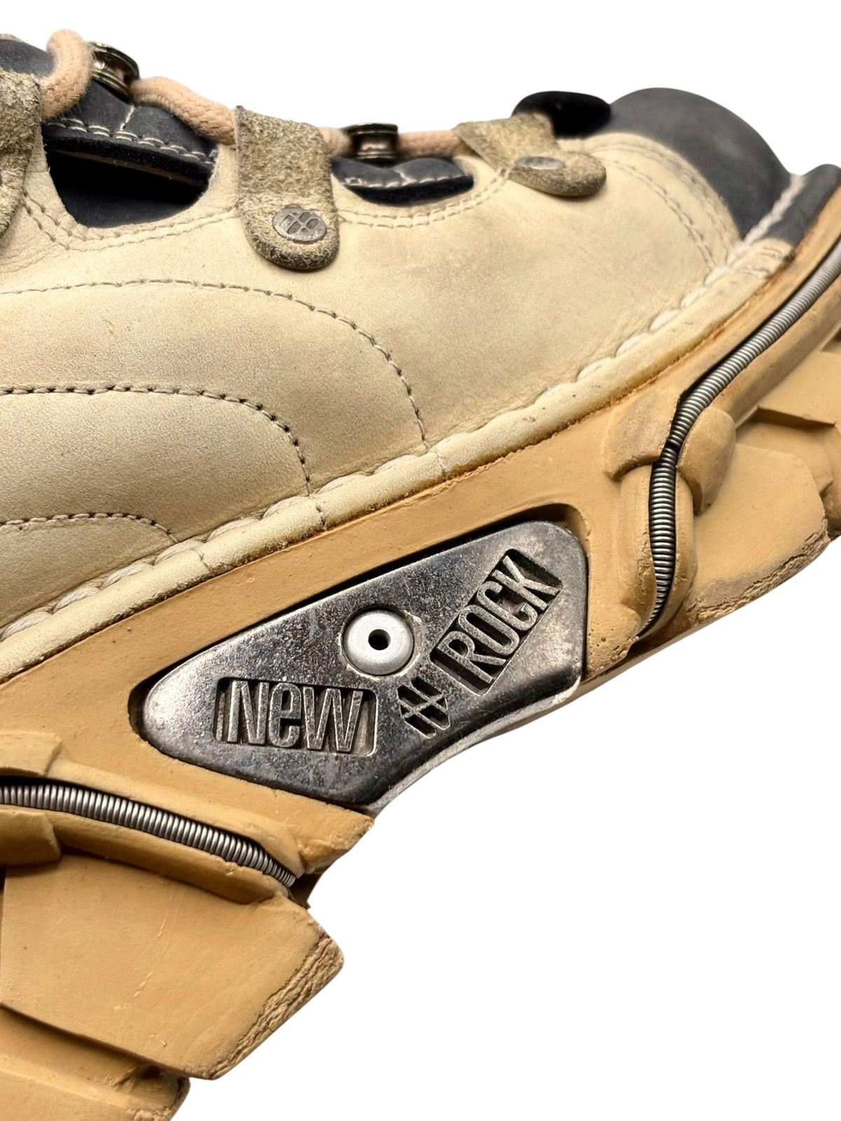 Close-up of beige leather platform boot strap with “NEW ROCK” metal logo plate