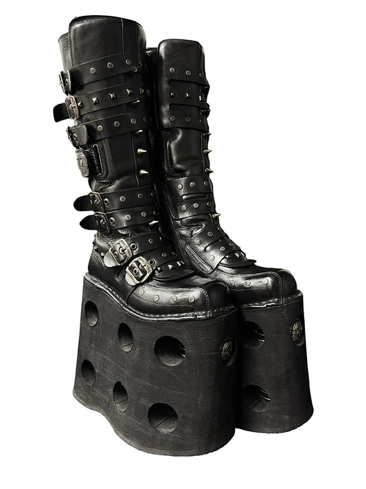 Black studded knee-high platform boots with strap buckles and cutout chunky sole