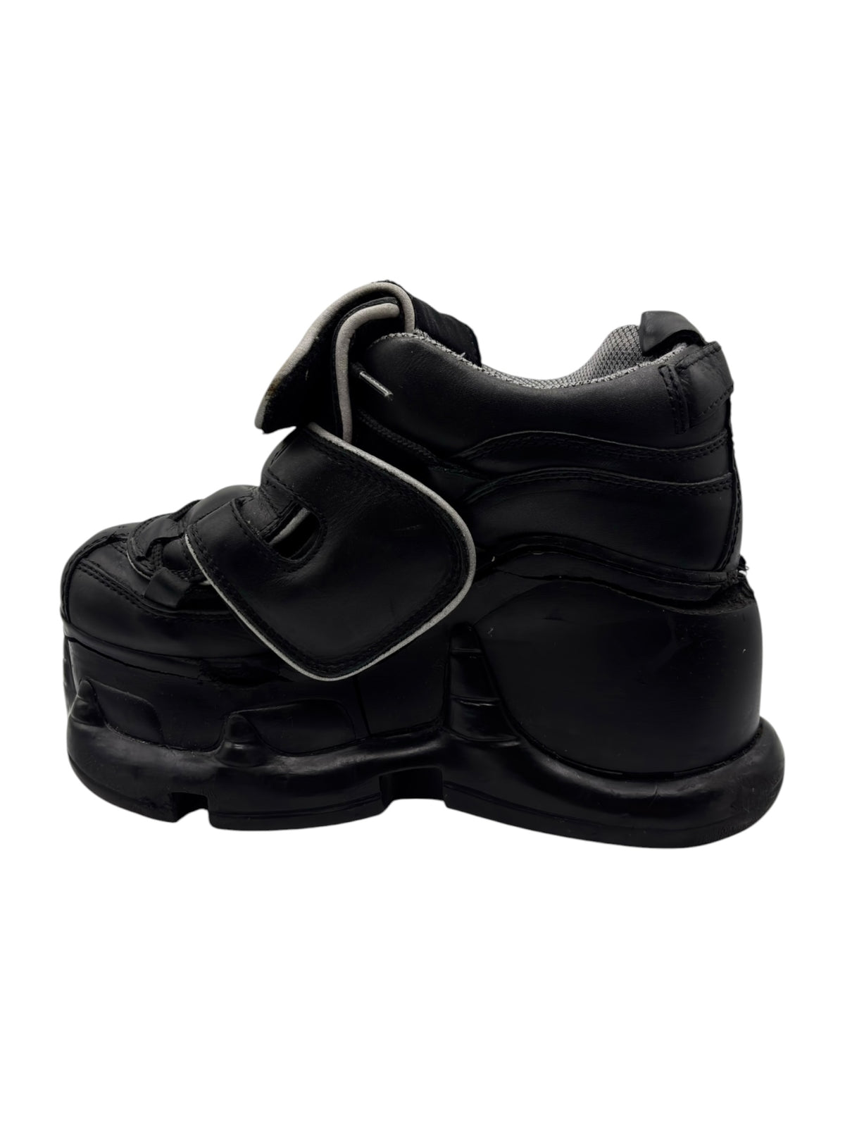 Black platform boots with front strap and thick lug sole, side-by-side view.