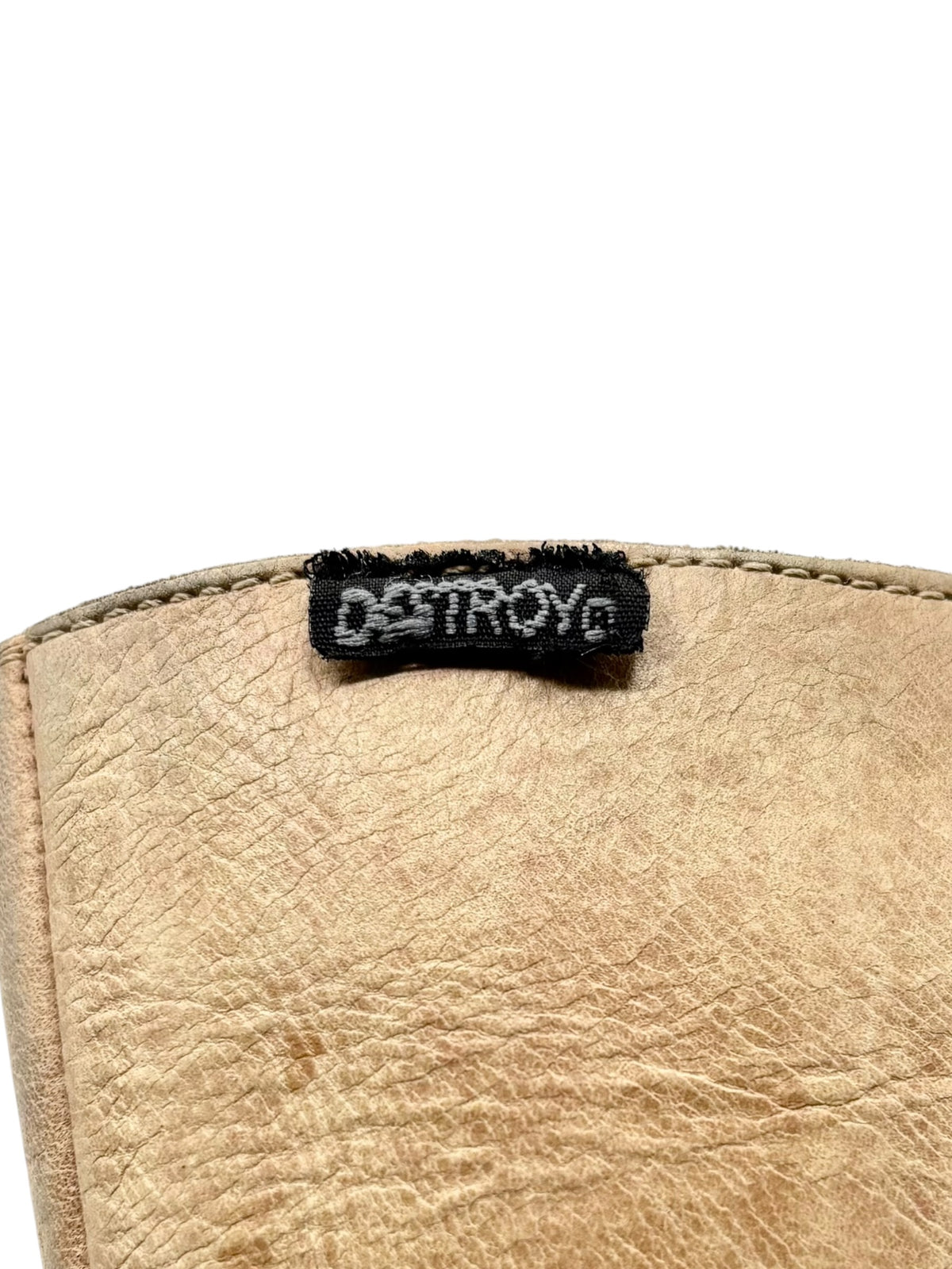 Beige leather boot collar label patch with DESTROY logo on stitched edge.