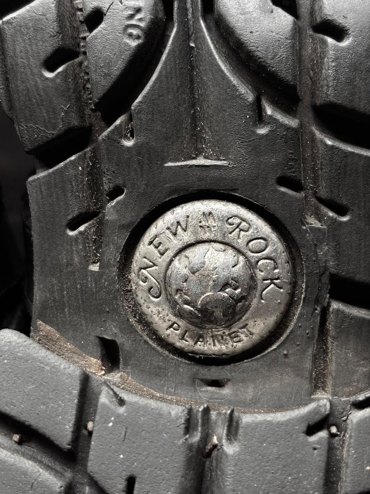 Boot outsole tread with circular logo medallion on dark rugged rubber sole