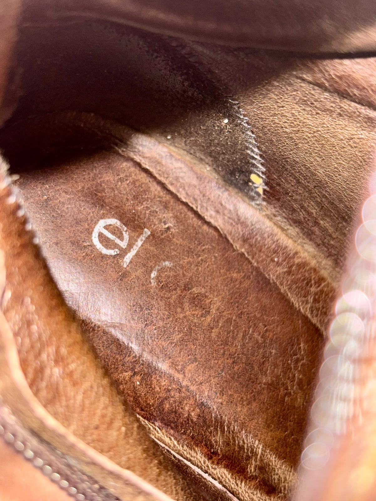 Boot lining close-up in tan with seam stitching and small embossed logo.