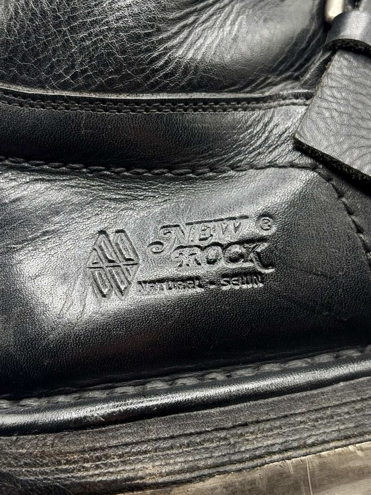 Black leather boot side panel with stitched logo emblem