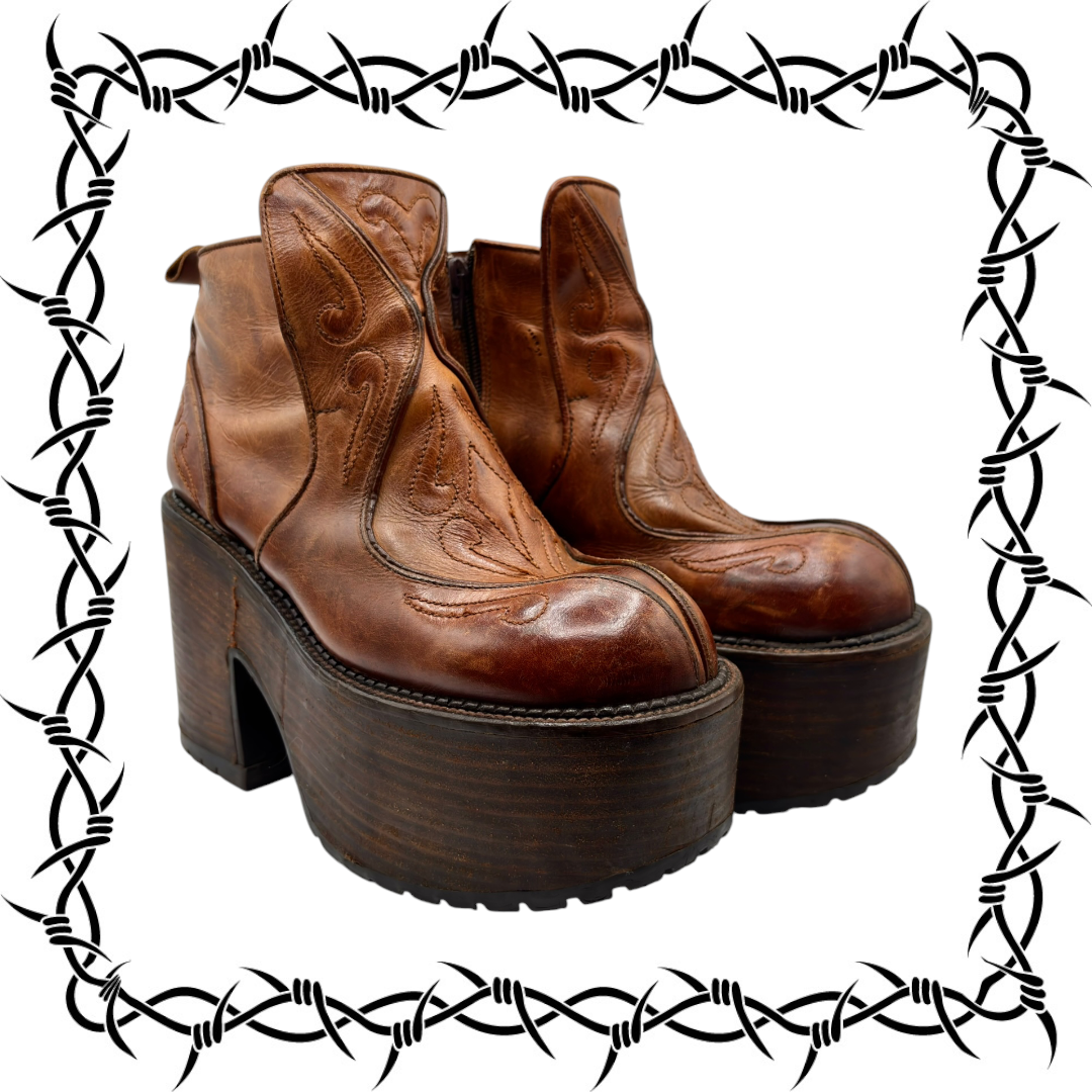 Pair of brown leather platform ankle boots with decorative stitching and side zipper