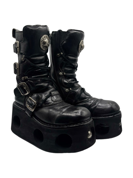 Black mid-calf platform boots with chunky sole, side buckles, round emblem