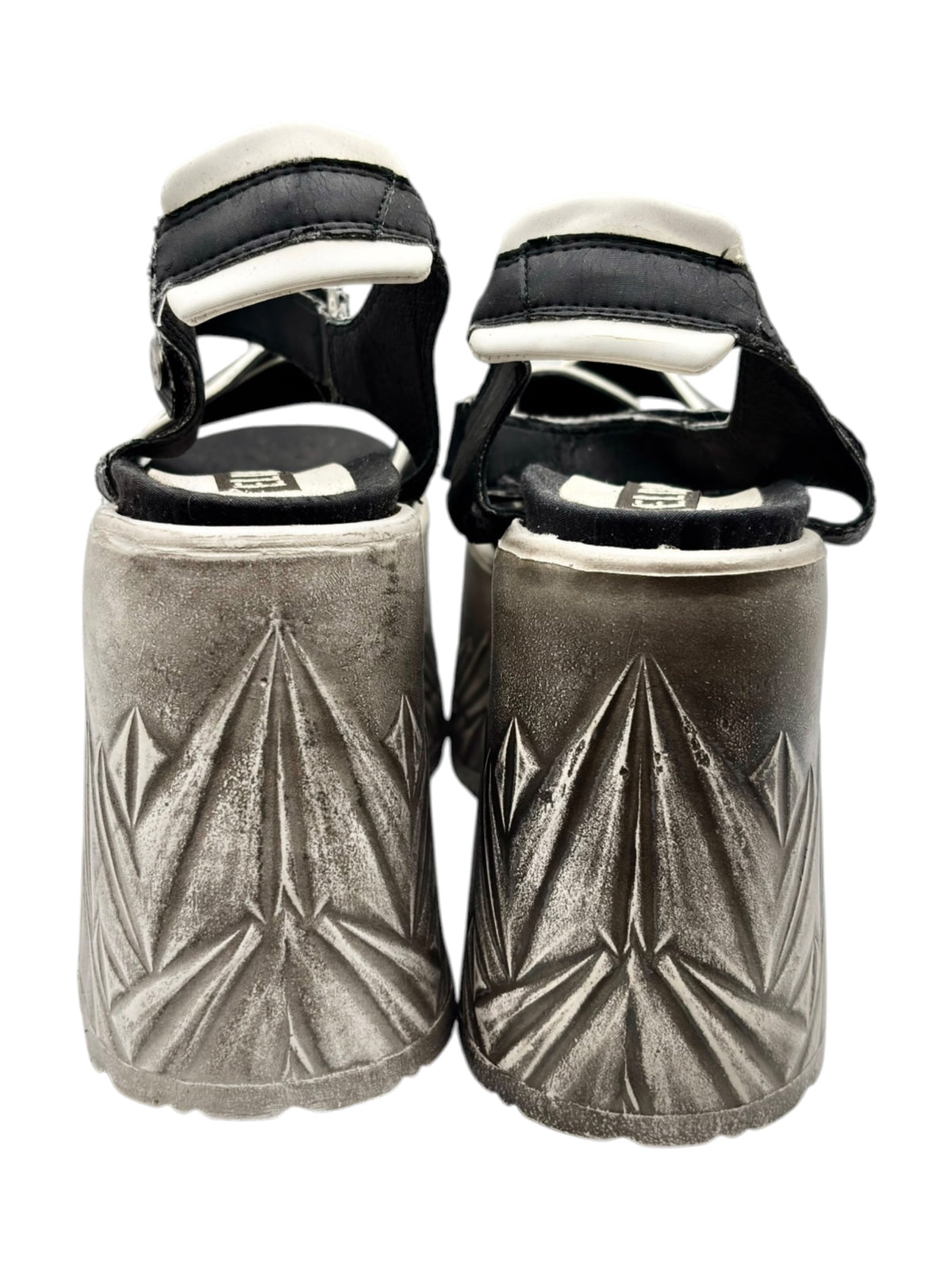 Back view of two platform sandals with black straps and silver embossed pattern