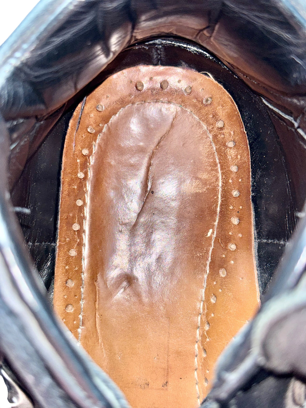 Boot interior footbed with stitched tan lining under the black leather upper