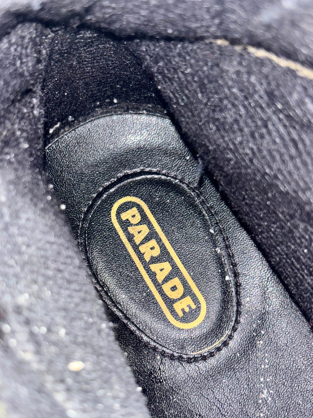 Brown leather boot with black interior patch and yellow-bordered logo text