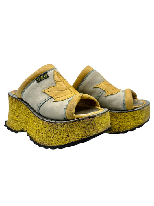 Angled view of gray and yellow platform sandals with wide straps and textured wedge sole