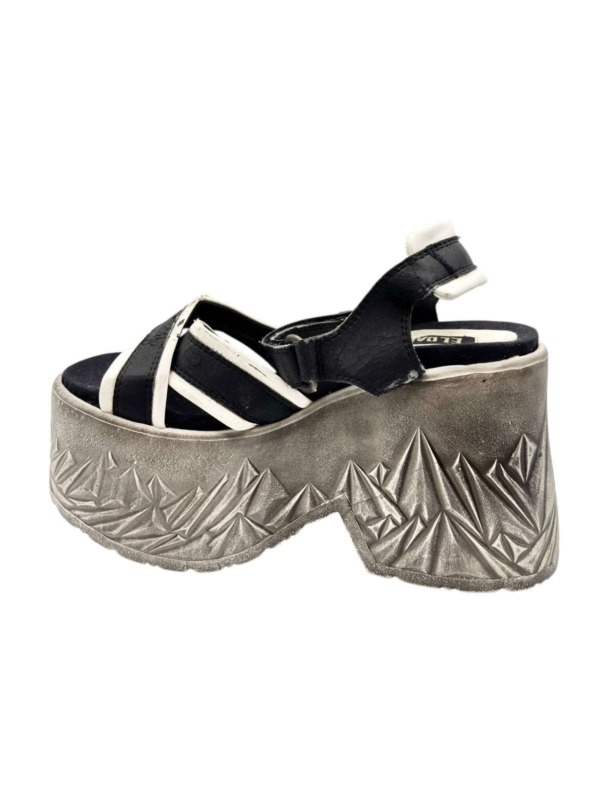 Black sandal with white crisscross straps and silver textured platform